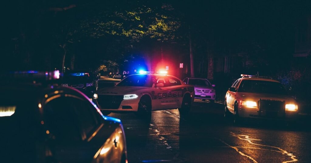 Viaturas de polícia com giroflex ligado em rua à noite, cenário do trabalho de segurança pública e inteligência